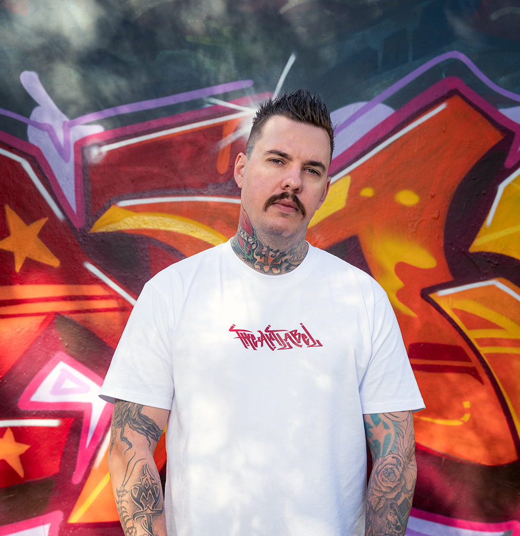 Master Murals half-body shot wearing his self-designed wearable art collection with THE ART LABEL in the front