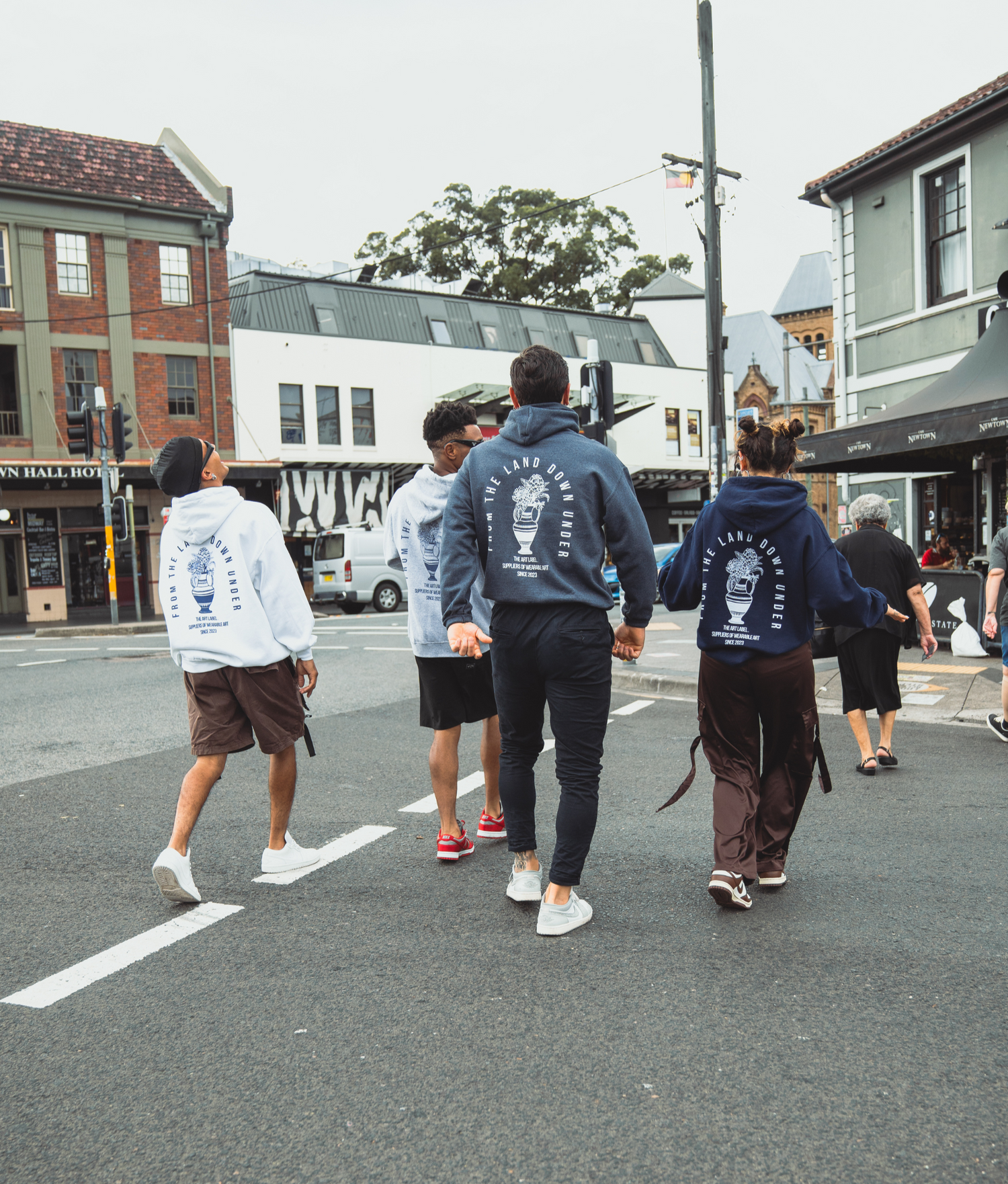 a group of friends walking over the street wearing wearable art