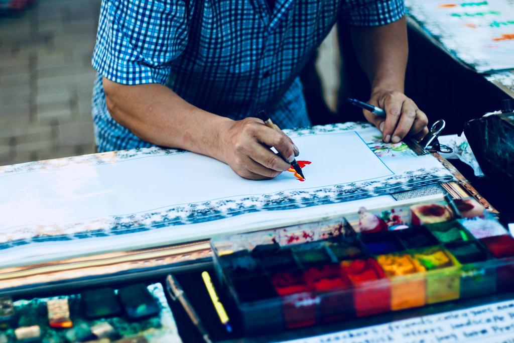 a guy is painting on paper with watercolours