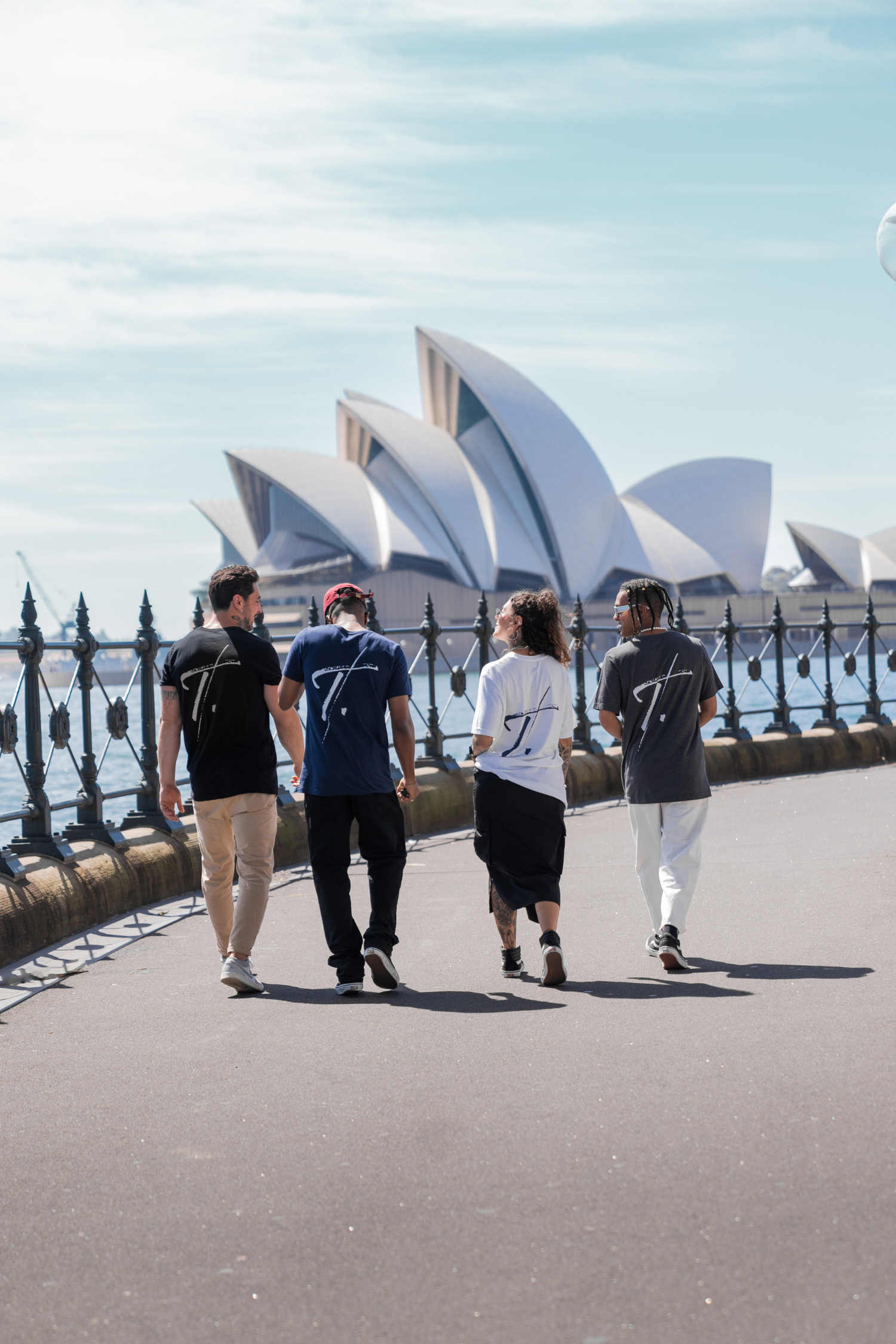 A group of people walking towards the Sydney Opera House while wearing wearable art from THE ART LABEL